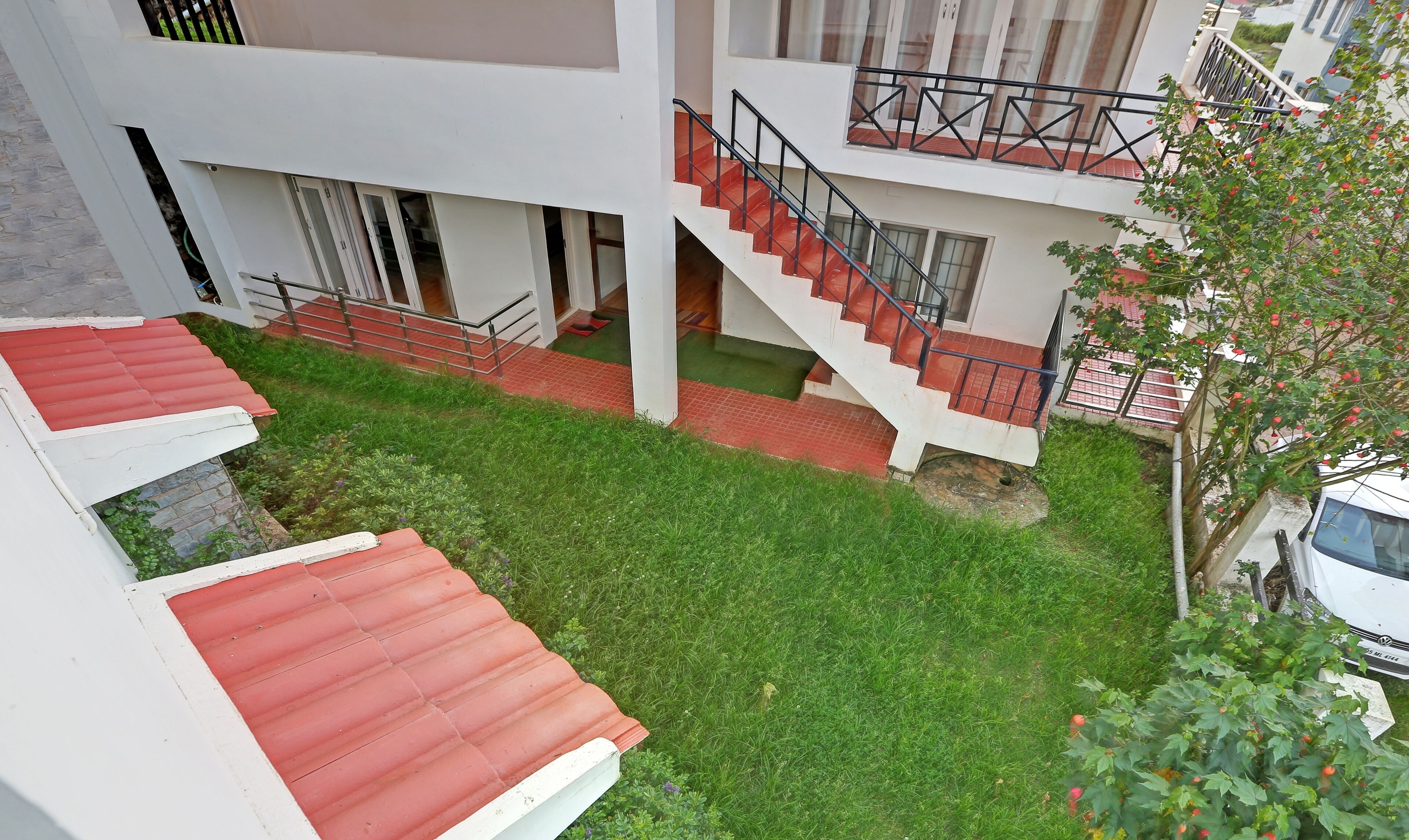 A multi-level building with a red-tiled roof, a staircase with metal railings, and a green lawn area.