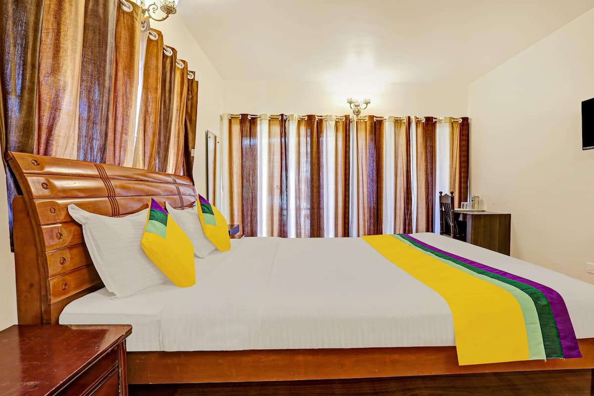 Una habitación de hotel con una cama de madera, cortinas, un televisor y una mesita de noche.