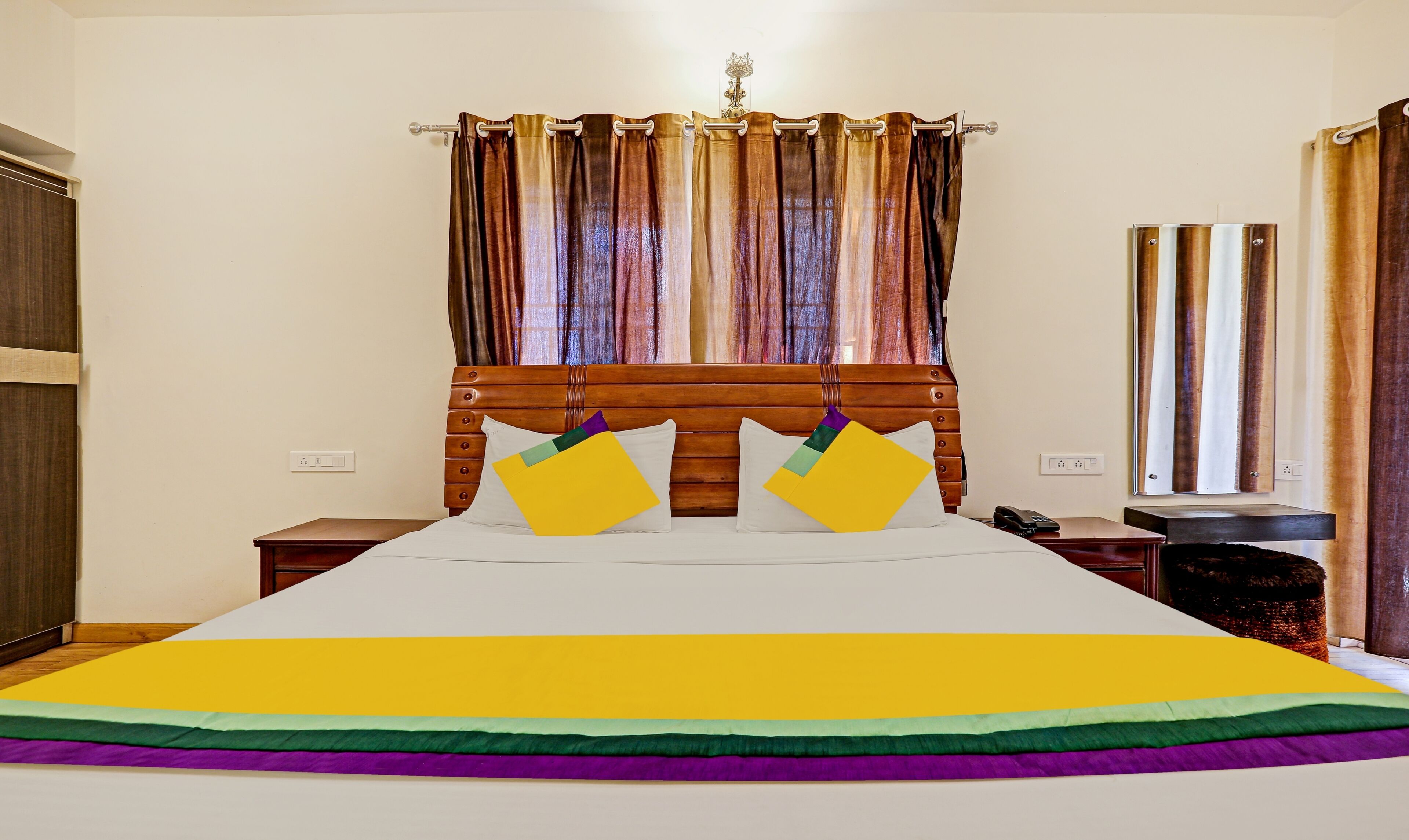 A hotel room with a large bed, wooden headboard, and curtains.