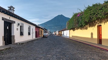 A cobblestone street lined with traditional buildings, a mountain in the background, and a clear sky.
