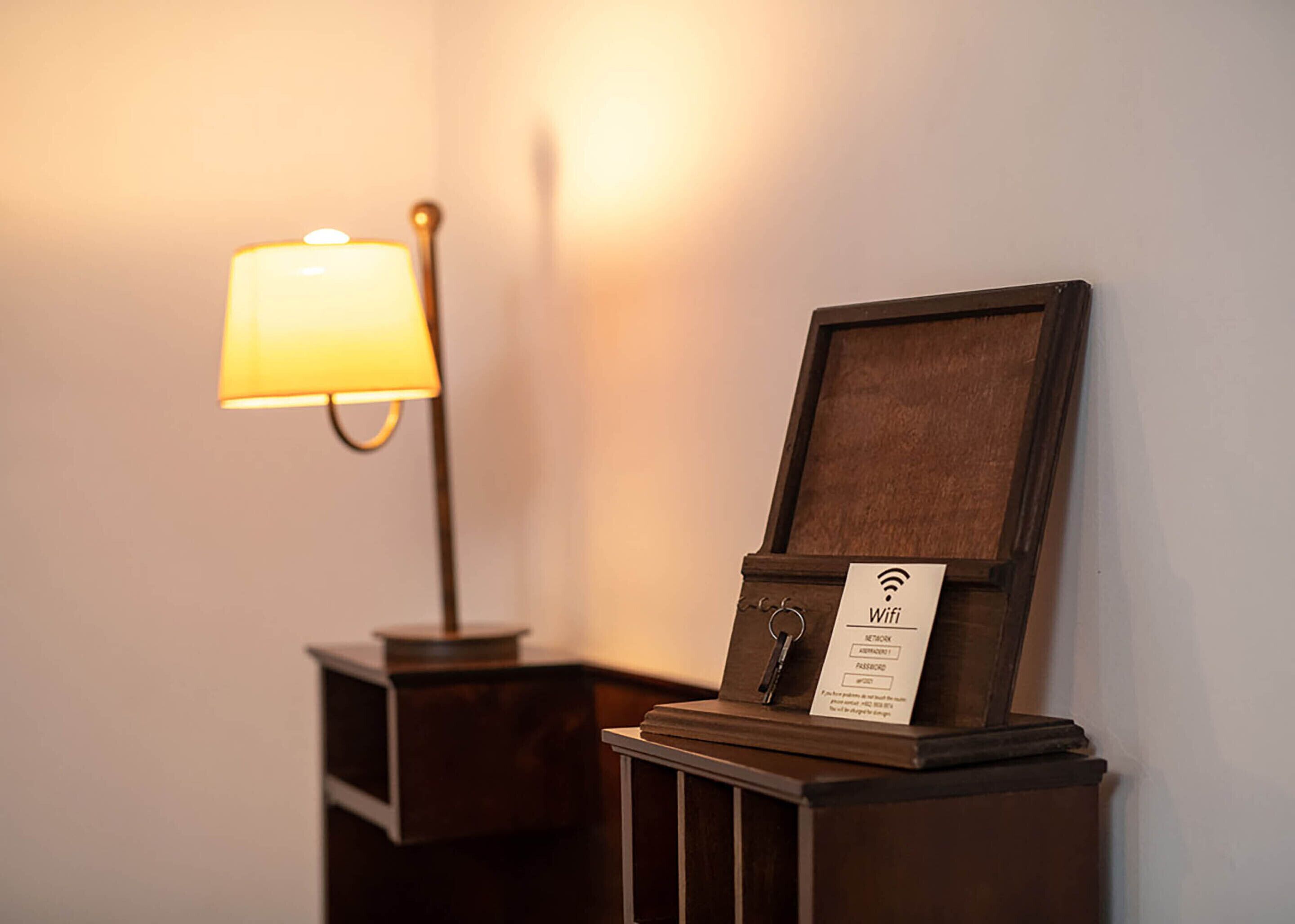 A wooden nightstand with a lamp and a sign indicating WiFi availability.
