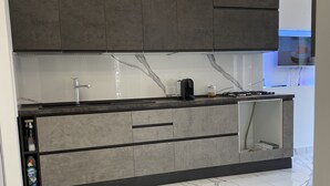 Une cuisine moderne avec des meubles gris, un plan de travail en marbre et une cuisinière intégrée.