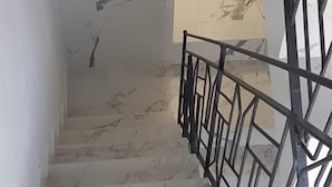 Un escalier en marbre avec une rampe métallique menant à l’étage supérieur.
