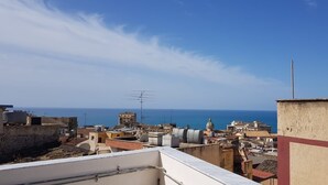 Un paysage urbain côtier, avec des bâtiments et des antennes, donnant sur la mer.