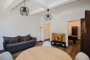 A modern living room with a gray sofa, a wooden dining table, and a painting on the wall. - Alloro Apartment - Three Bedroom Apartment, Sleeps 6 (Firenze)