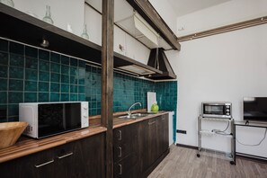 Eine moderne Küche mit dunklen Holdschränken, einer weißen Mikrowelle, einer Edelstahl-Spüle und einem eingebauten Backofen.