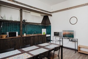 Una cocina moderna con armarios de madera oscura, salpicadero azul aguamarina y un comedor con mantel estampado.