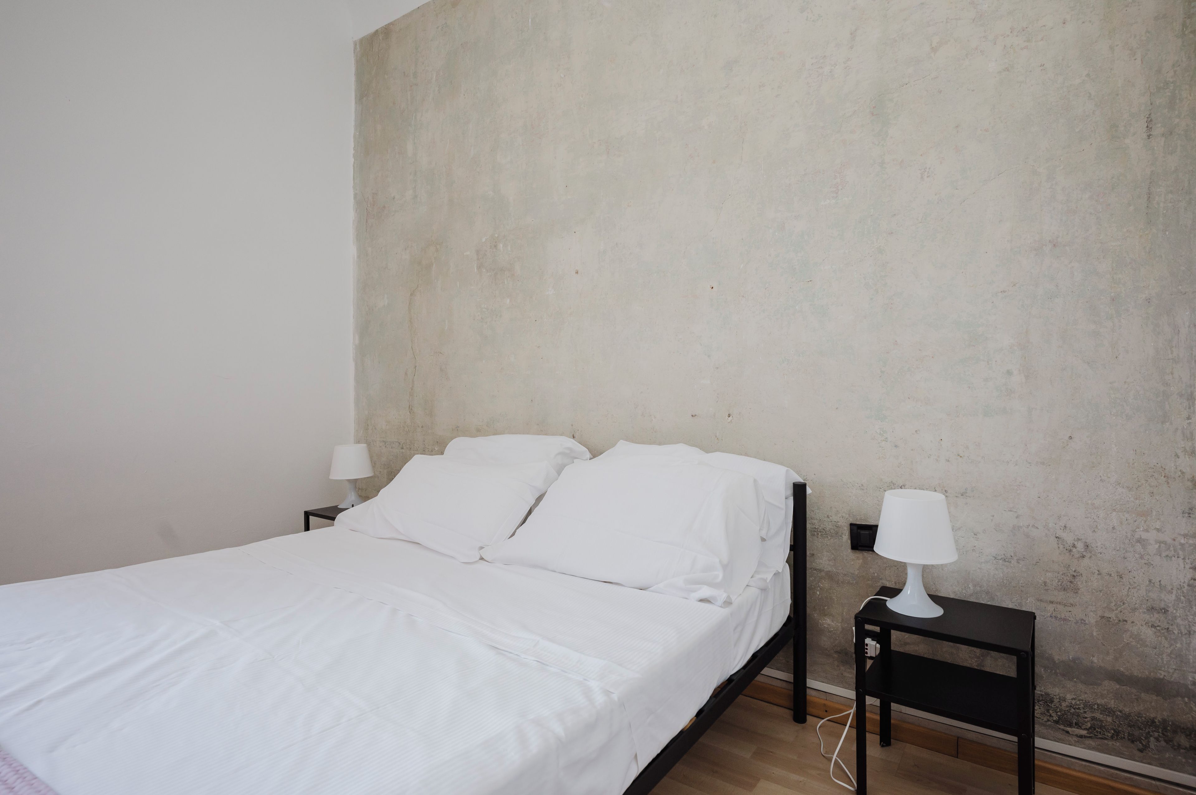 Une chambre à coucher minimaliste avec un lit simple, deux tables de chevet et un mur uni.
