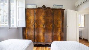 Ein Schlafzimmer mit zwei Betten, einem Holzschrank und einem Fenster mit Blick.