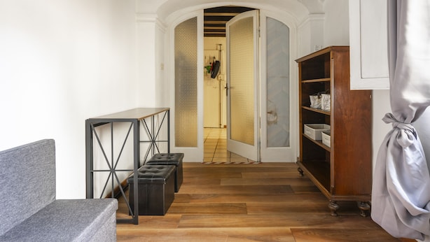 Ein Flur mit einem grauen Sofa, einem schwarzen Metalltisch und einem Holzschrank.
