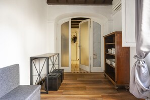 A hallway with a grey sofa, a black metal table, and a wooden cabinet. - Ginori C - Three Bedroom Apartment, Sleeps 6 (Firenze)
