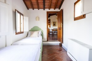 A bedroom with a bed, a green headboard, a radiator, and a window with a wooden frame. - Piazza Santa Croce - Two Bedroom Apartment, Sleeps 4 (Firenze)