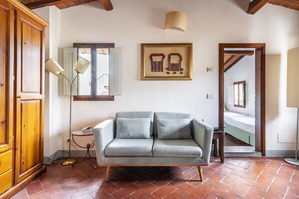 A room with a light grey sofa, wooden wardrobe, and a framed picture on the wall. - Piazza Santa Croce - Two Bedroom Apartment, Sleeps 4 (Firenze)