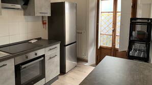 Une cuisine moderne dotée d’un réfrigérateur en acier inoxydable, d’un four encastré et de meubles de rangement gris.