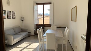 Une pièce comprenant un canapé, une table à manger, des chaises, un lampadaire et une fenêtre donnant sur un beau paysage.