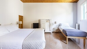 Hotellihuone, jossa on kaksi sänkyä, työpöytä, vaatekaappi ja patteri.