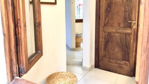 A wooden door with a brass handle, a woven basket on the floor, and a framed picture on the wall. - Martiri del Popolo 28 (Firenze)
