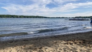 A beach with calm water, a dock, and a distant shoreline with trees. - Secluded in the Woods, Hot Tub (Twin Lakes)