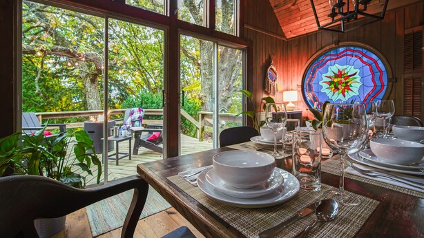 A dining area with a view of the outdoors, a large stained glass window, and a wooden ceiling. - Secluded in the Woods, Hot Tub (Twin Lakes)