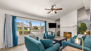 A modern living room with teal sofas, a coffee table, and a fireplace.