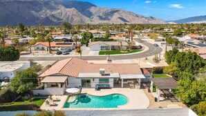 A residential area with houses, a swimming pool, and mountains in the background.