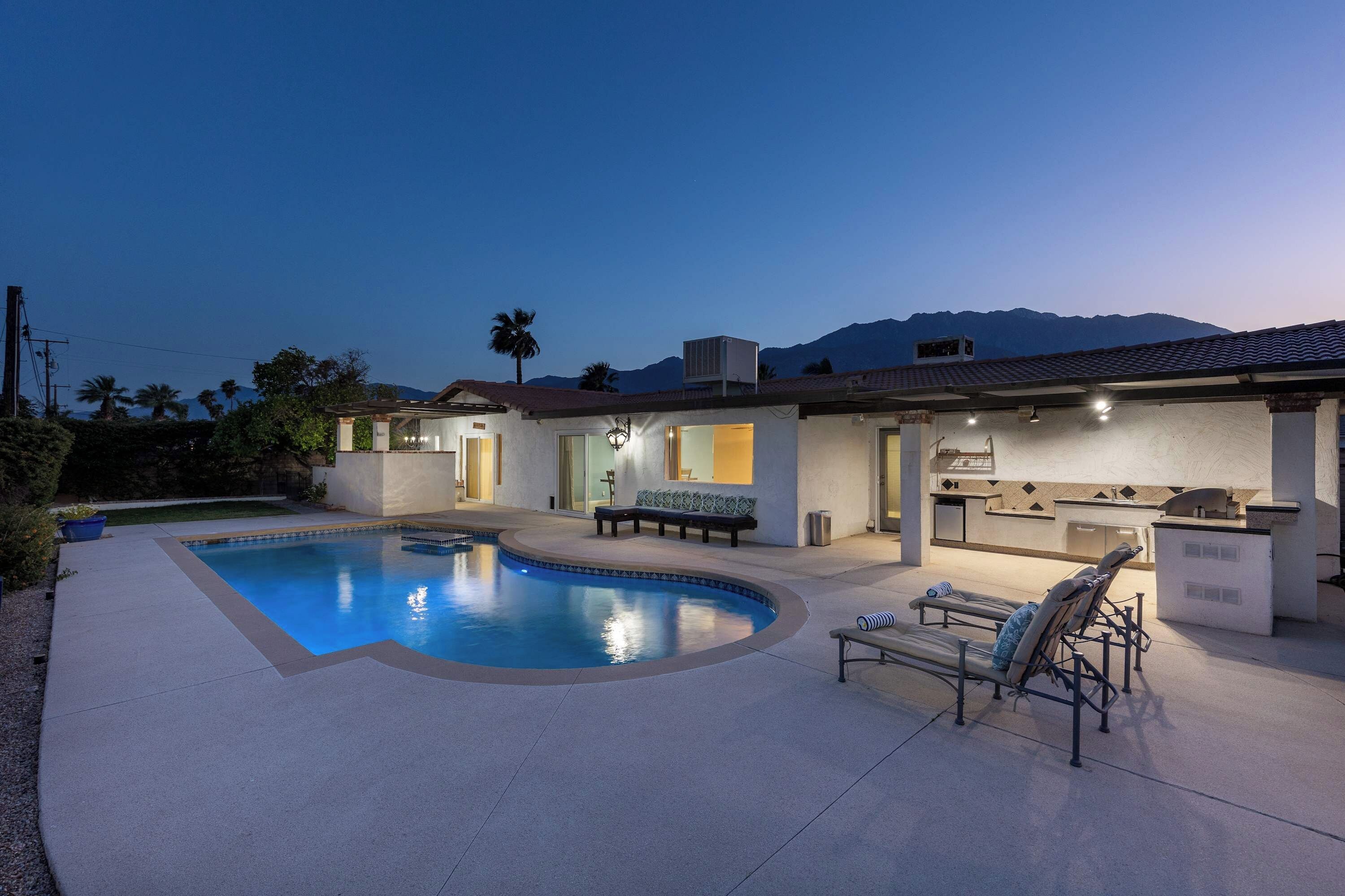 A residential property with a swimming pool, outdoor seating, and a barbecue area.
