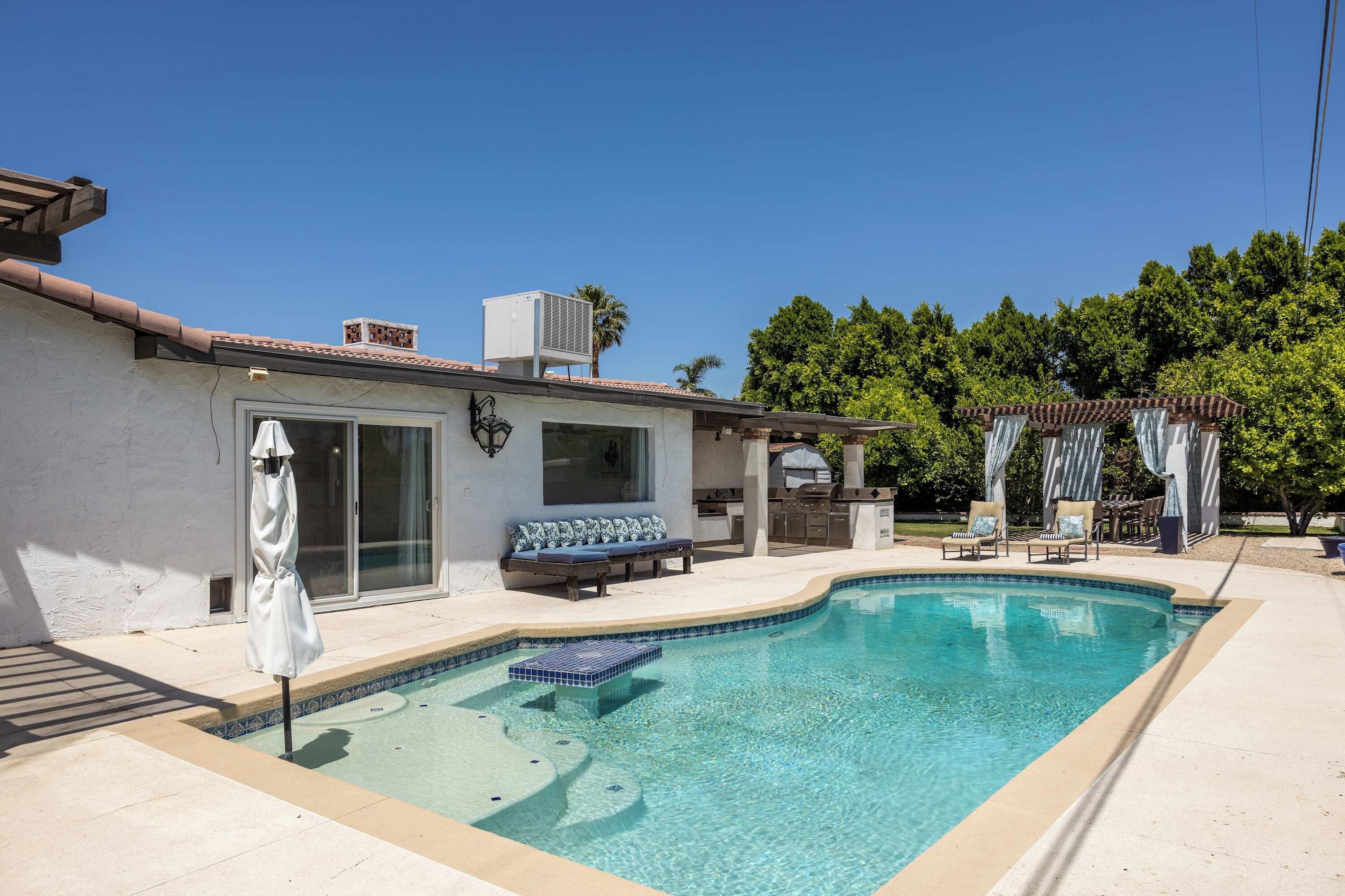 Curved backyard pool beside the house and covered outdoor seating.