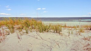 A beach with sand and sparse vegetation. - 45 Ocean Point by Avantstay Amazing Views + Beach Access & Community Pool Access (Isle of Palms)