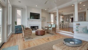 A spacious living room with a fireplace, wicker furniture, and a ceiling fan. - 45 Ocean Point by Avantstay Amazing Views + Beach Access & Community Pool Access (Isle of Palms)