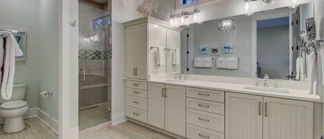 A modern bathroom with a walk-in shower, a large vanity with a mirror, and a toilet.