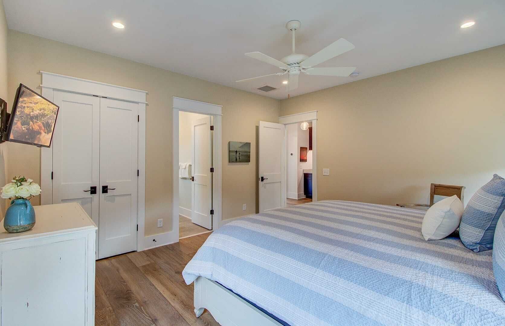 Une chambre à coucher avec un lit, un ventilateur de plafond et une commode.