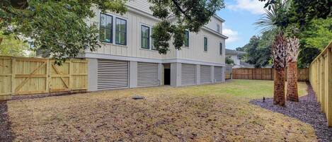 A two-story house with a covered garage, a fenced yard, and a palm tree.
