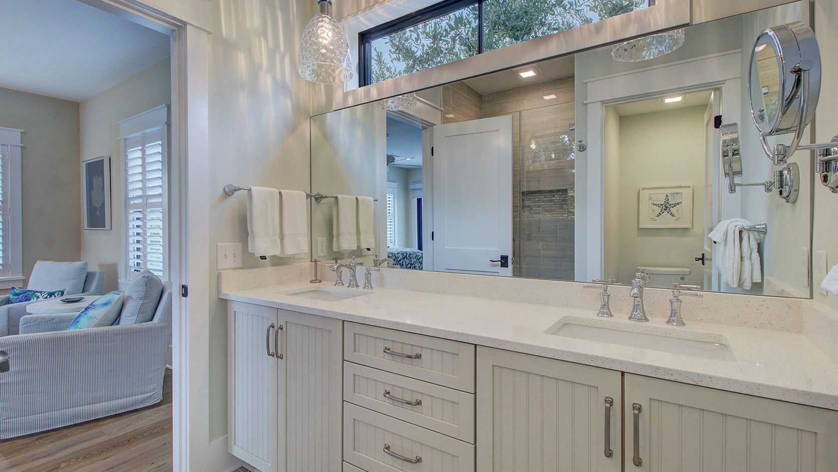 Un baño moderno con un espejo grande, lavamanos doble y cabina de ducha a ras de suelo.