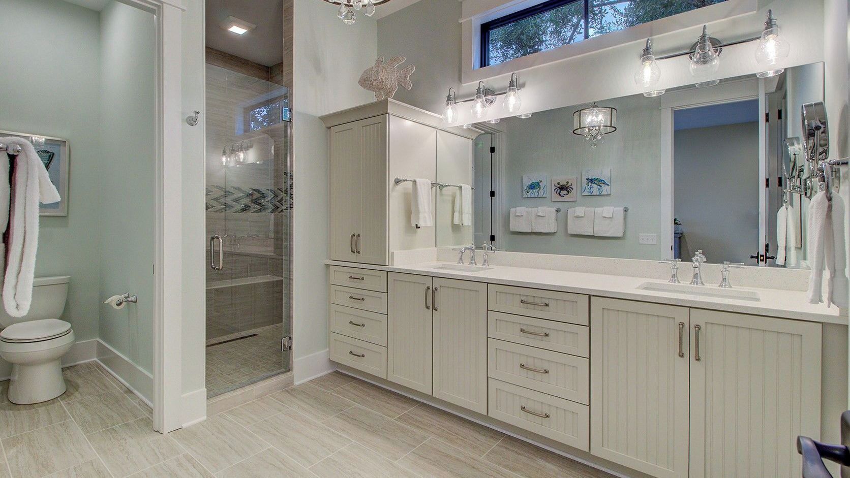 A modern bathroom with a walk-in shower, a large mirror, and a vanity with drawers.
