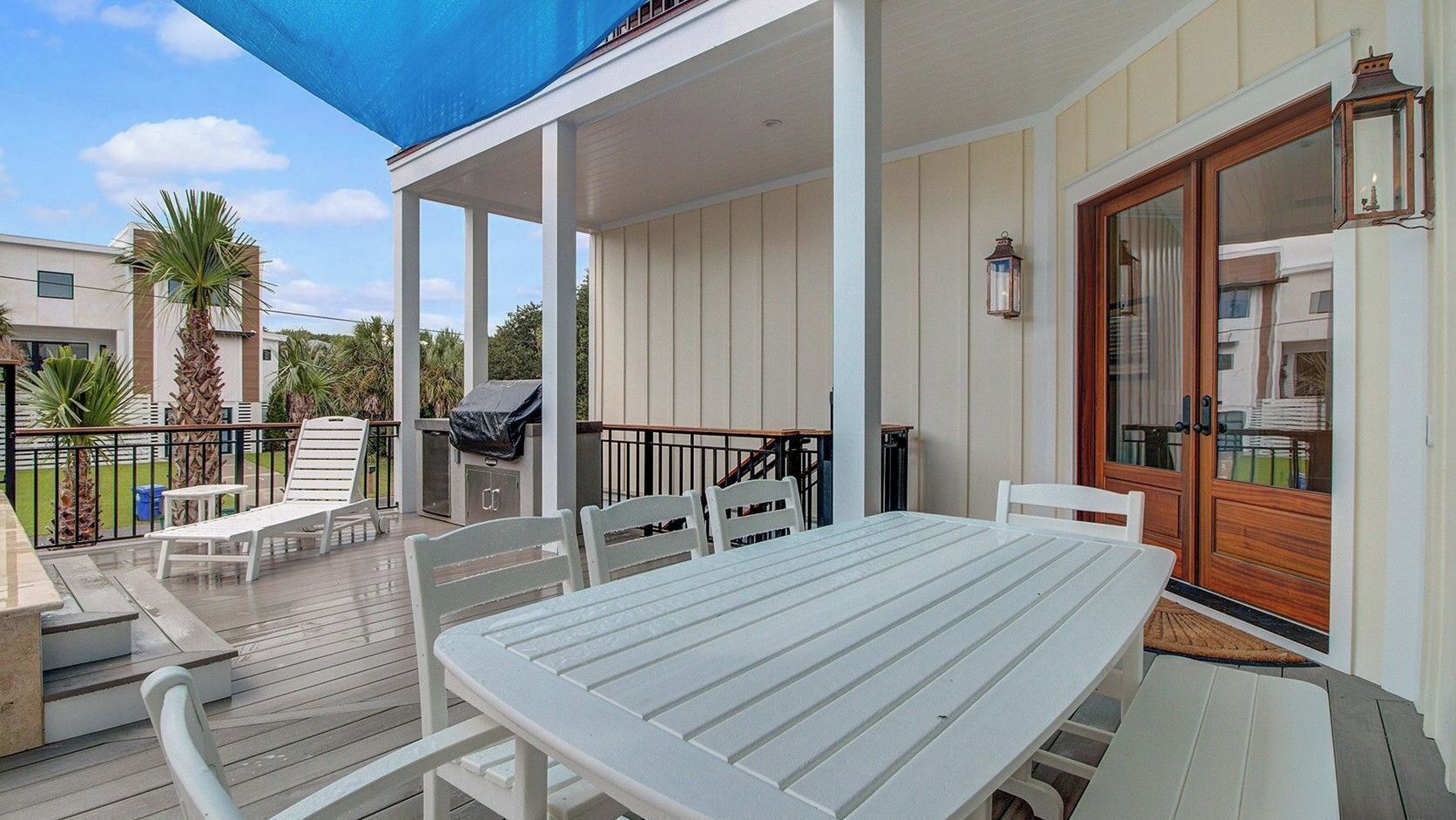 A covered outdoor patio with a table and chairs, a grill, and a view of the surrounding buildings.