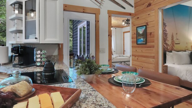 A cozy kitchen with a coffee maker, a cheese board, and a dining area with a table set for two. - Lake, Golf & Hike at Linville Lodge in  Linville  Land  Harbor  Resort Community (Newland)