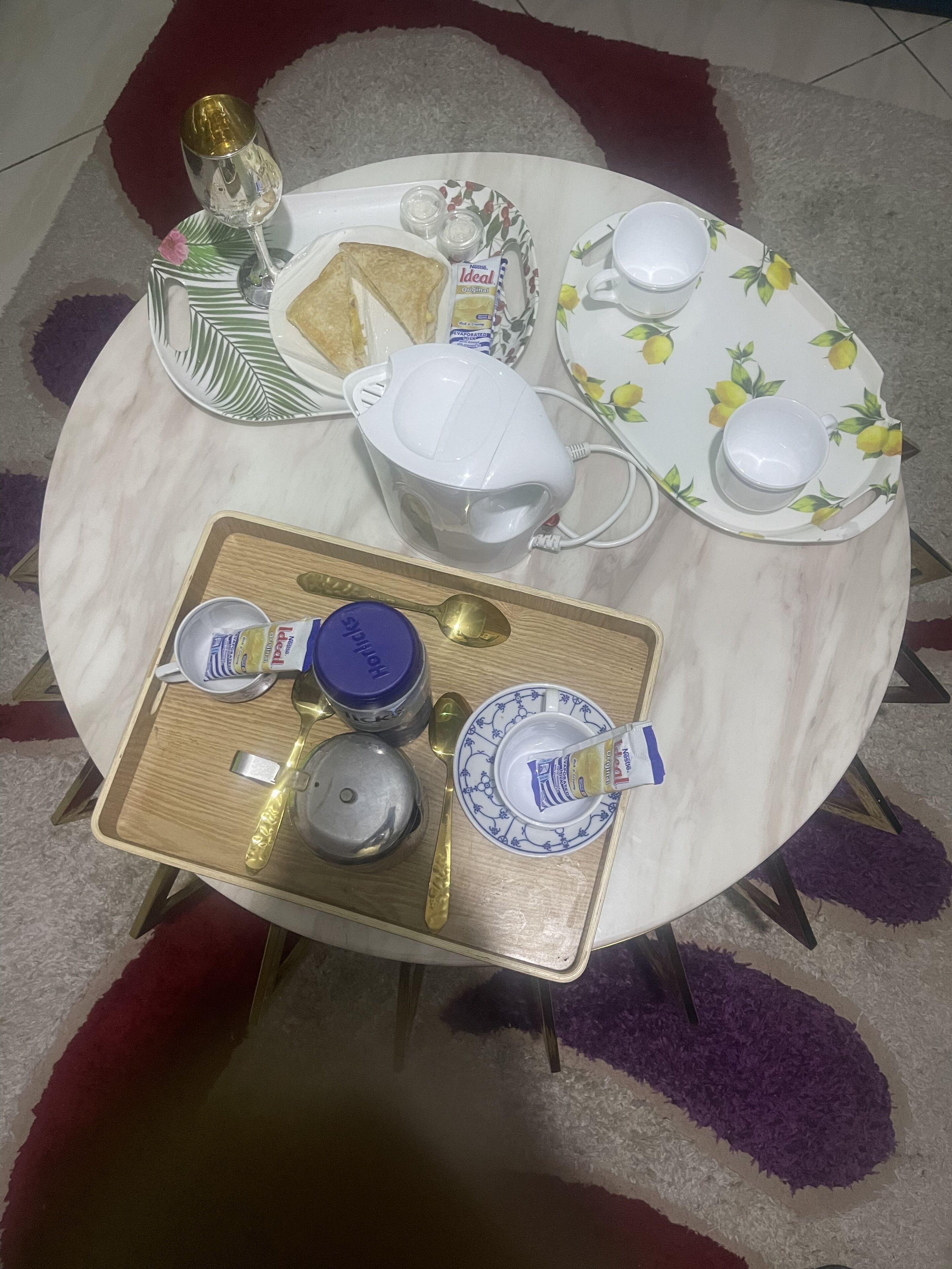 A table set with various items including a teapot, cups, a jug, and a tray with condiments.