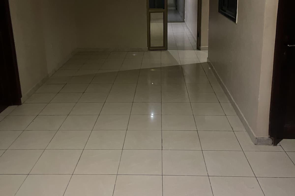 A spacious room with a tiled floor, a door leading to another area, and a framed picture on the wall.