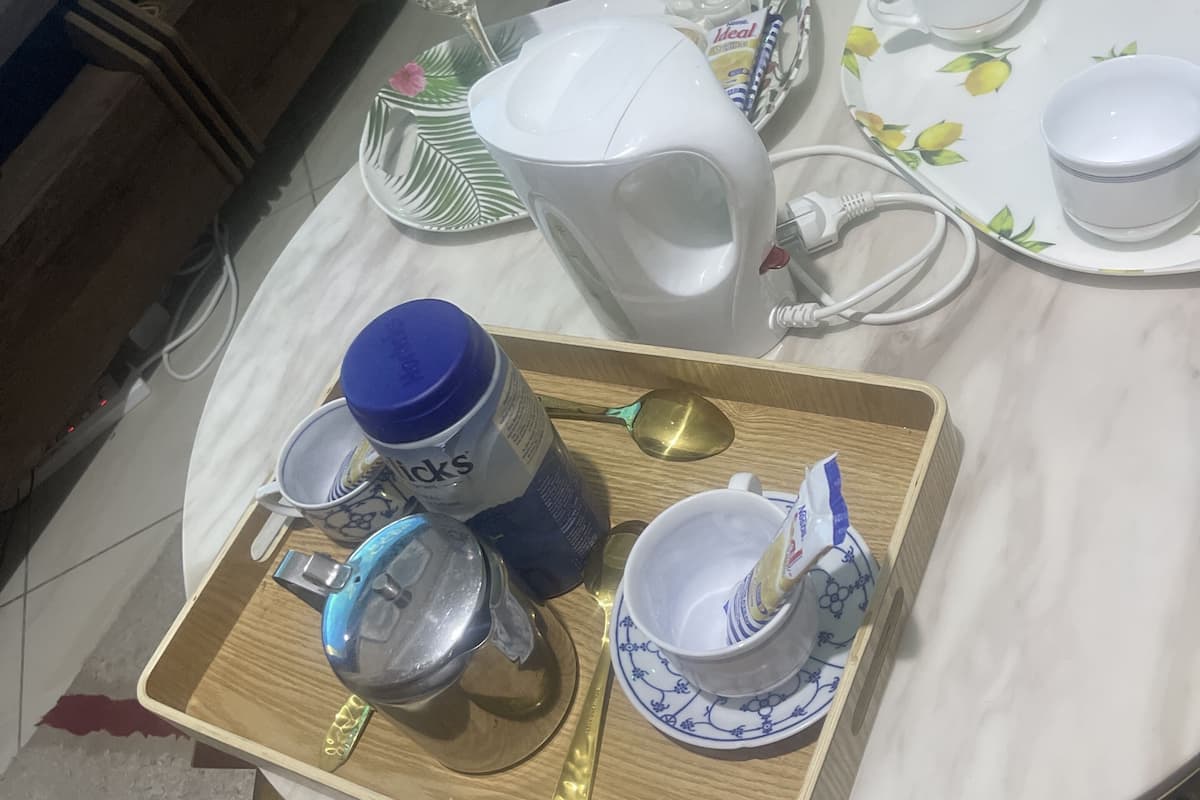 A dining table with a tray holding a water bottle, a cup, and a spoon.