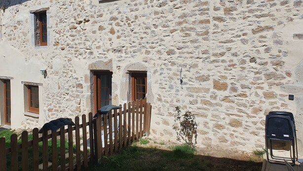A stone building with multiple windows and a wooden fence.