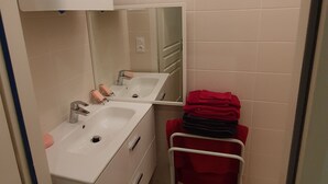 A bathroom with two sinks, a mirror, and a towel rack with folded towels.