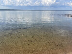 A clear view of a beach with shallow water revealing sand and small rocks. - Peaceful, private Ottertail Lake Retreat (Battle Lake)