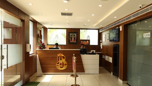 Zona de recepción de un hotel con un mostrador de madera, un logotipo iluminado y un cartel que indica los primeros y segundos pisos.