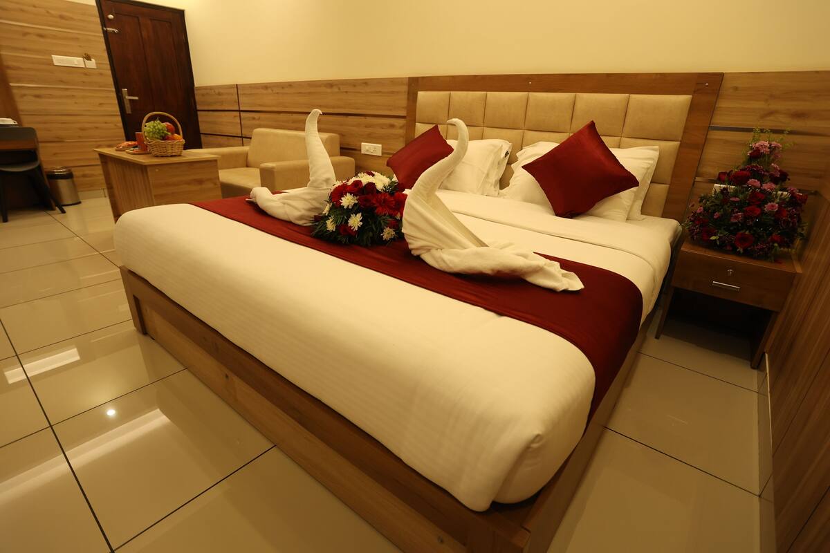 Ein Hotelzimmer mit einem großen Bett, einem hölzernen Kopfteil, einem Nachttisch mit einem Korb und einem Beistelltisch mit Blumen.