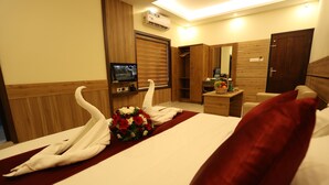 Habitación de hotel con cama, televisión, armario, escritorio y un espejo, además de una cesta de fruta.
