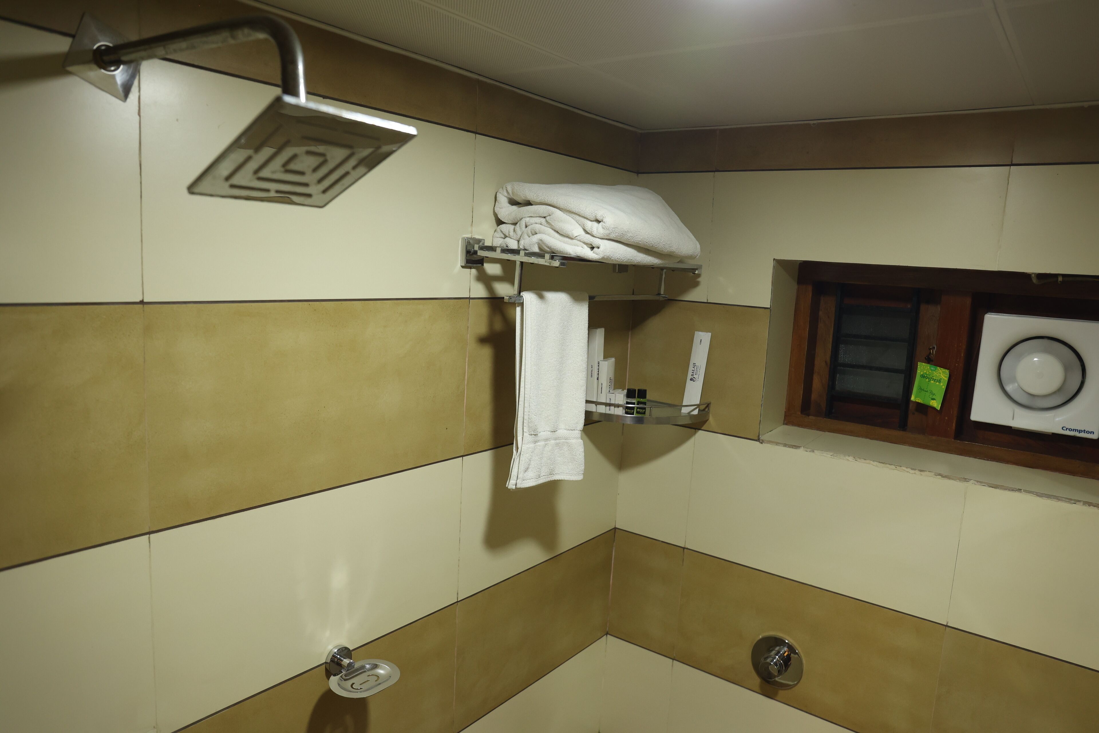 A bathroom with a shower, a towel rack, and a washing machine.