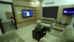 Una sala de estar moderna con un televisor de pantalla plana, sofás cómodos, una mesita de centro con flores y un panel de pared de madera.
