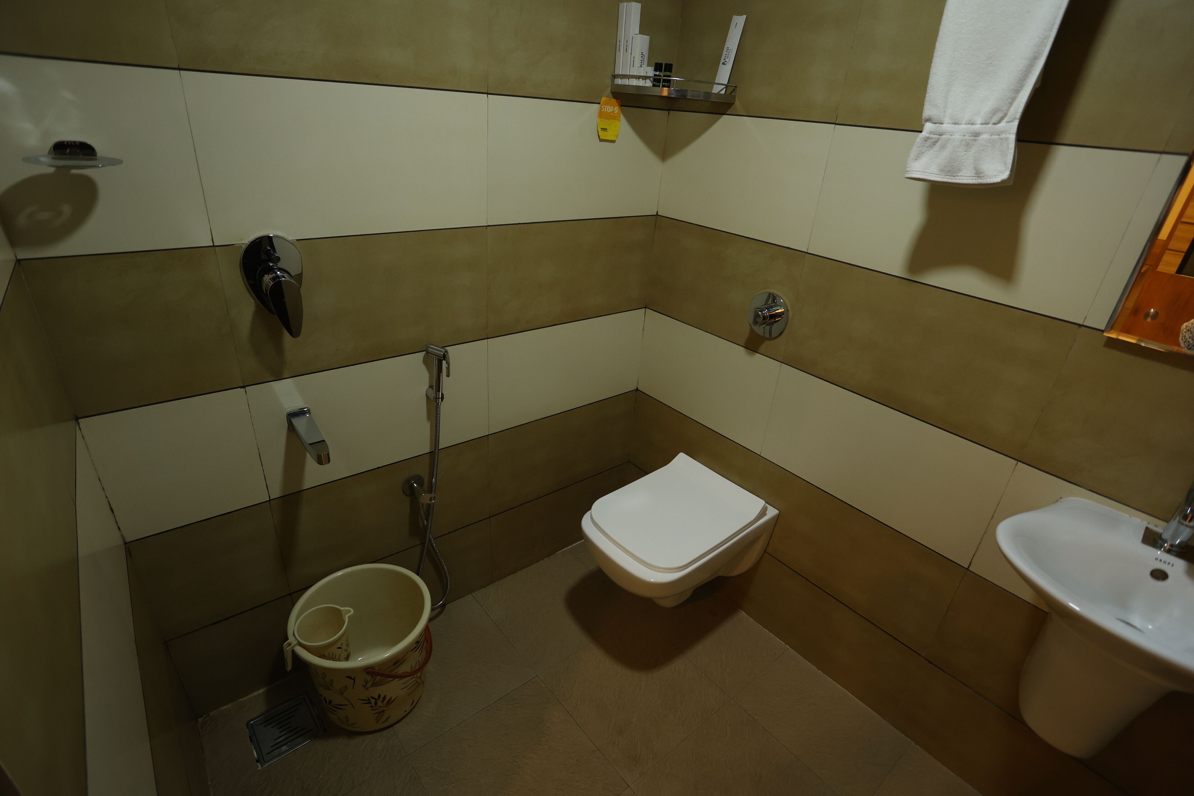 Un baño pequeño y funcional con inodoro, bidé, lavamanos y un cubo de basura.