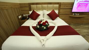 A neatly made bed with a heart-shaped towel arrangement and a floral centerpiece.