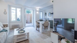 Un soggiorno moderno con divano, tavolino e TV. C'è un'area cucina con tavolo e sedie da pranzo.